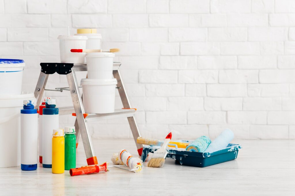 Painting supplies with ladder and paints against bricks wall